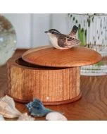 Aufbewahrungsdose Zaunkönig von Wildlife Garden aus Holz mit leicht geöffnetem Runddeckel und geschnitztem Vogel, auf einem Tisch mit Muscheln.