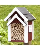 Bienenhotel Biholk Rot von Wildlife Garden auf einem Holzpfosten im grünen Garten, mit roter Holzfassade, weißen Dachleisten und hohlen Niströhren.