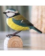 DecoBird Blaumeise aus Holz von Wildlife Garden mit blauer Kopfkappe, weißen Wangen, gelber Brust und blaugrünen Flügeln auf einem Baumstamm.