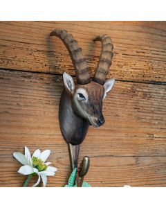Kleiderhaken Alpensteinbock von Wildlife Garden an einer rustikalen Holzwand, mit braunem Steinbockkopf, langen gerippten Hörnern und Metallhaken.