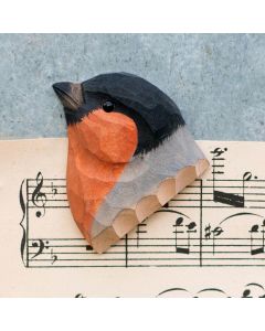 Kühlschrankmagnet Gimpel aus Holz von Wildlife Garden mit schwarzem Kopf, orange-roter Brust und grauem Flügel auf einem Notenblatt.