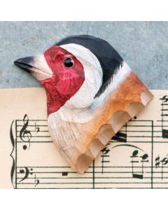 Kühlschrankmagnet Stieglitz aus Holz von Wildlife Garden mit roter Gesichtsmaske, schwarz-weißem Kopf und braunem Gefieder auf einem Notenblatt.