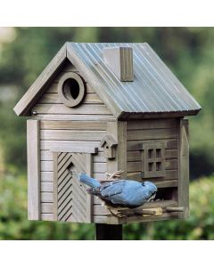 Kleiber mit blaugrauem Gefieder und schwarzem Augenstreif an der Futteröffnung des Multiholk Grüne Umbra von Wildlife Garden, mit rundem Einflugloch und braungrüner Holzfassade.