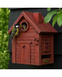 Kohlmeise mit grüner Raupe im Schnabel füttert einen Jungvogel am Einflugloch des Multiholk Rote Erde von Wildlife Garden, einem roten Nistkasten an einer dunklen Holzwand.