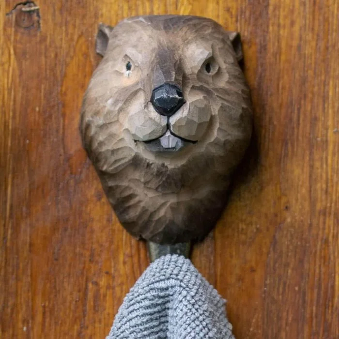 Kleiderhaken Biber von Wildlife Garden an einer Holzwand, mit geschnitztem braunem Biberkopf und einem grauen Handtuch am Metallhaken.