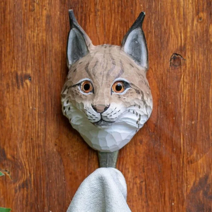 Kleiderhaken Luchs von Wildlife Garden an einer Holzwand, mit braun-weißem Luchskopf und einem hellen Handtuch am Metallhaken.