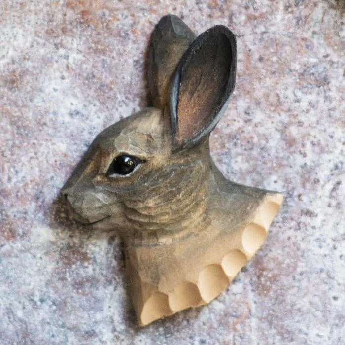 Kühlschrankmagnet Schneehase aus Holz von Wildlife Garden mit langen Ohren, dunklem Auge und graubraunem Fell auf einer hell gesprenkelten Metallfläche.